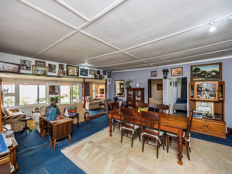 Spacious open-plan living and dining area featuring large windows, sliding glass doors to the exterior, and a traditional panelled ceiling.