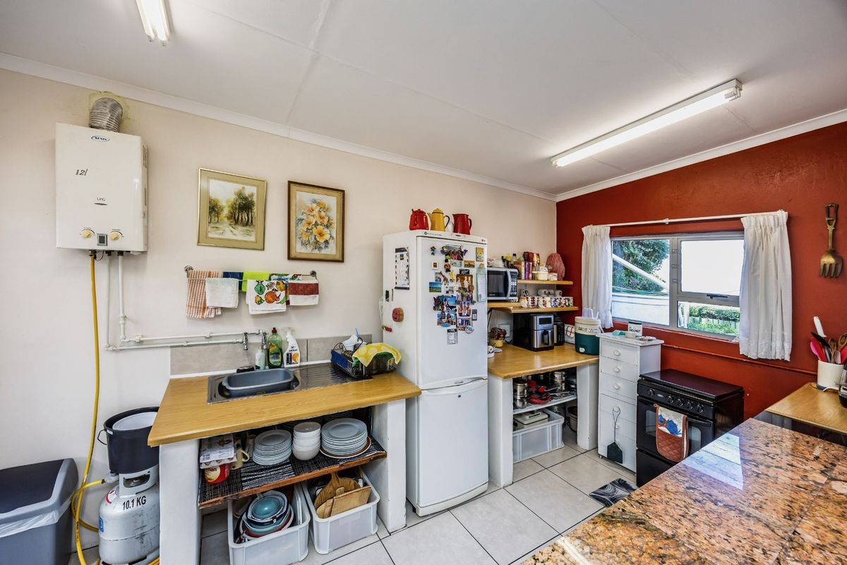 A functional kitchen area featuring a gas geyser, granite countertops, and tiled flooring, offering a practical layout with potential for modern updates.