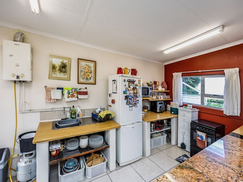 A functional kitchen area featuring a gas geyser, granite countertops, and tiled flooring, offering a practical layout with potential for modern updates.