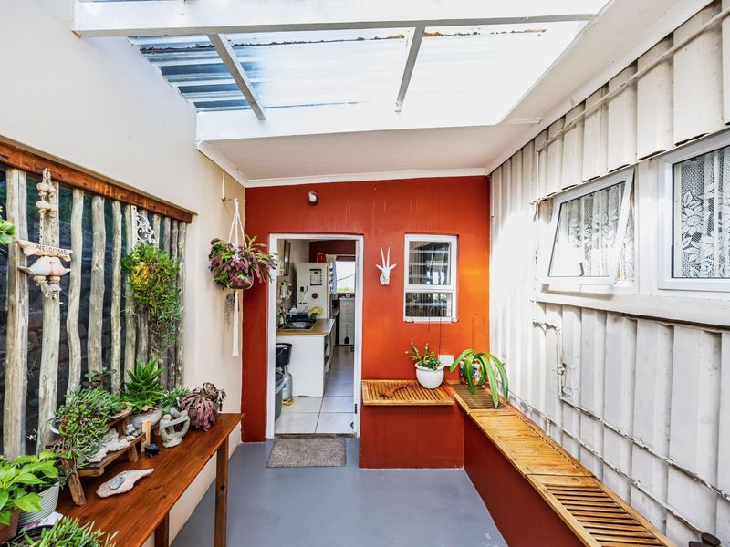 A covered patio area featuring a translucent roof, built-in timber bench seating, and direct access to the kitchen.