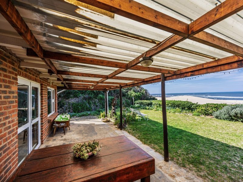 Covered outdoor patio featuring a timber pergola and concrete flooring, offering direct access to the garden with scenic ocean views.