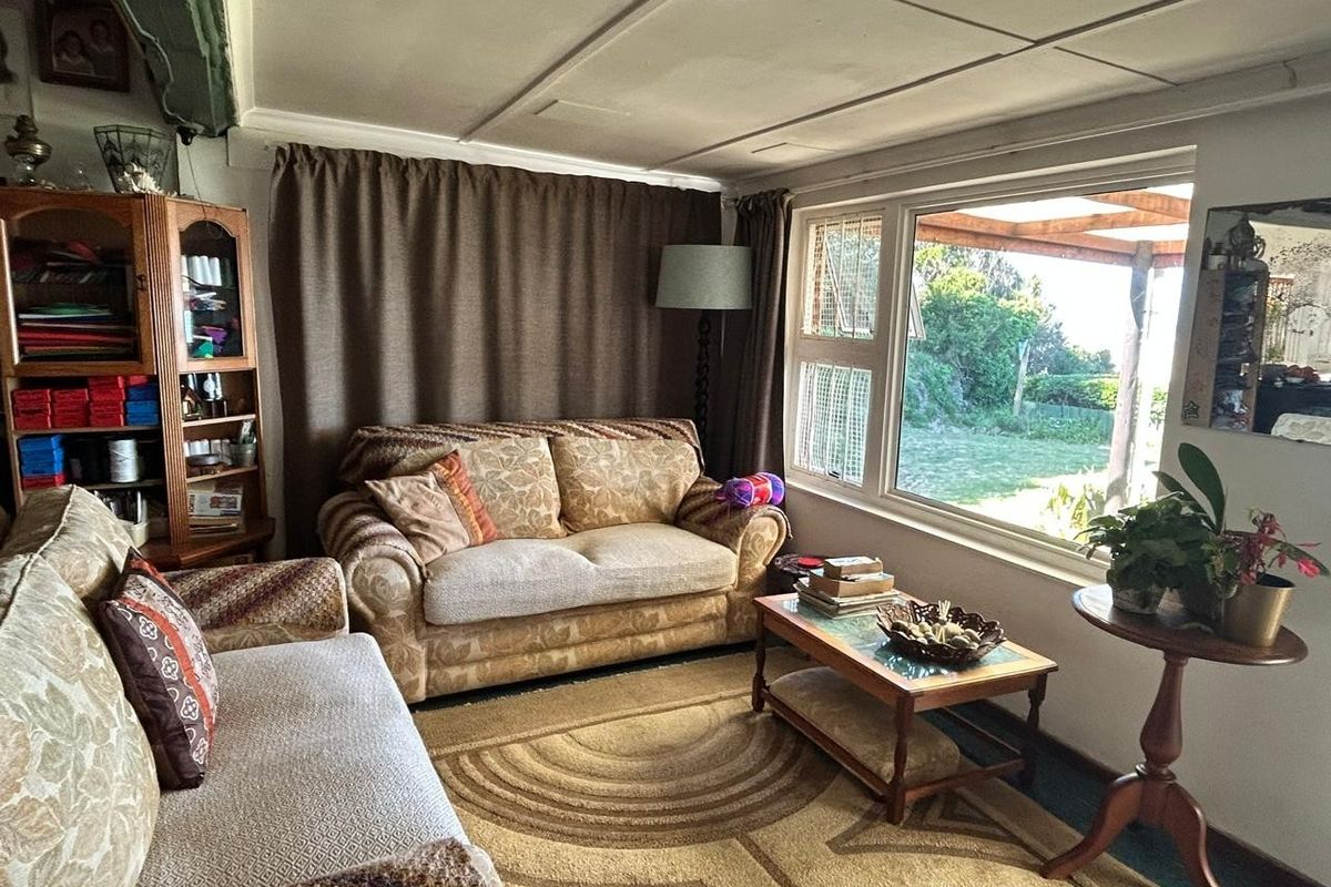 A cozy living room featuring a large window with garden views, neutral wall finishes, and a functional layout.