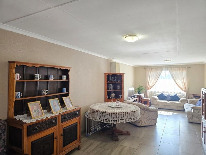 A spacious open-plan living and dining area featuring neutral wall tones and tiled flooring, offering a versatile layout for comfortable daily living.