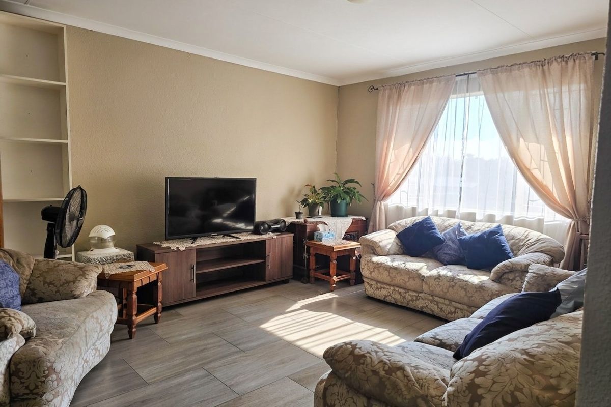 A comfortable living room featuring tiled flooring, built-in shelving, and large windows that provide ample natural light.