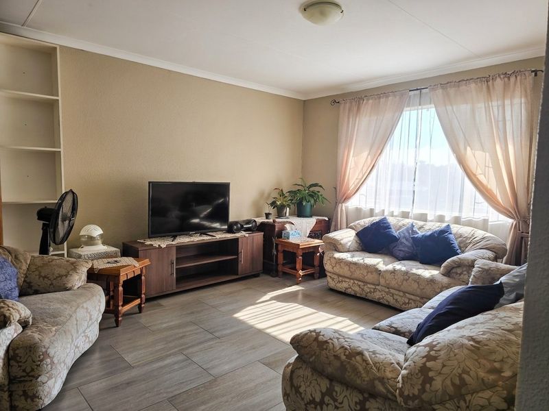 A comfortable living room featuring tiled flooring, built-in shelving, and large windows that provide ample natural light.