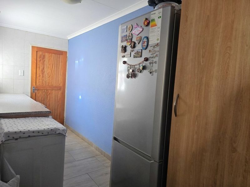 A functional laundry or utility area featuring tiled flooring, a built-in wooden cabinet, and a solid timber door.