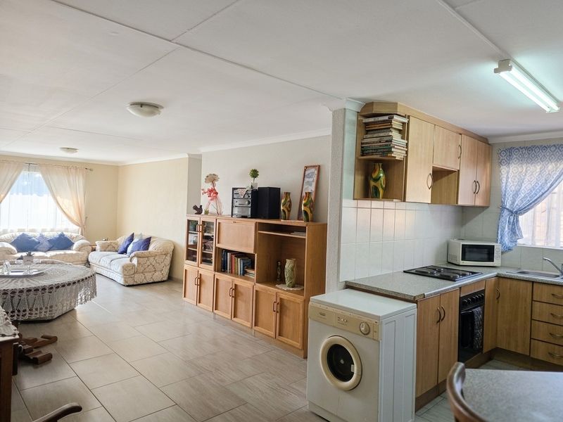 Open plan living area featuring a functional kitchen with built-in cabinetry, tiled flooring, and a connected lounge space.