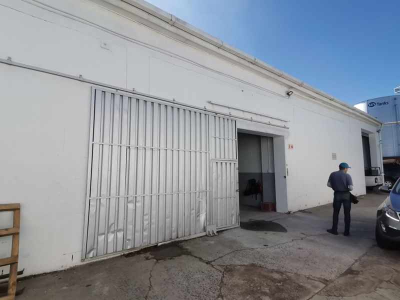 Exterior view of an industrial warehouse featuring a large sliding metal door, concrete apron, and white painted masonry walls.