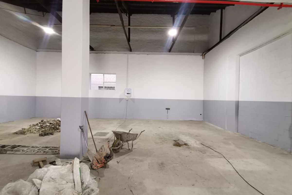 Spacious industrial utility space featuring high ceilings, exposed fire suppression piping, and a neutral two-tone wall finish, suitable for various commercial or storage applications.