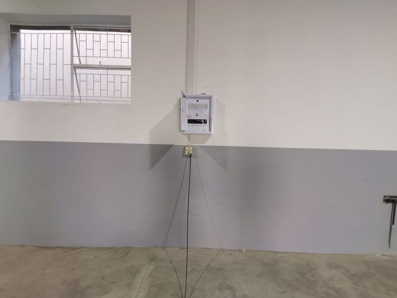 Industrial utility space featuring a wall-mounted electrical distribution board, power outlet, and security-barred window.
