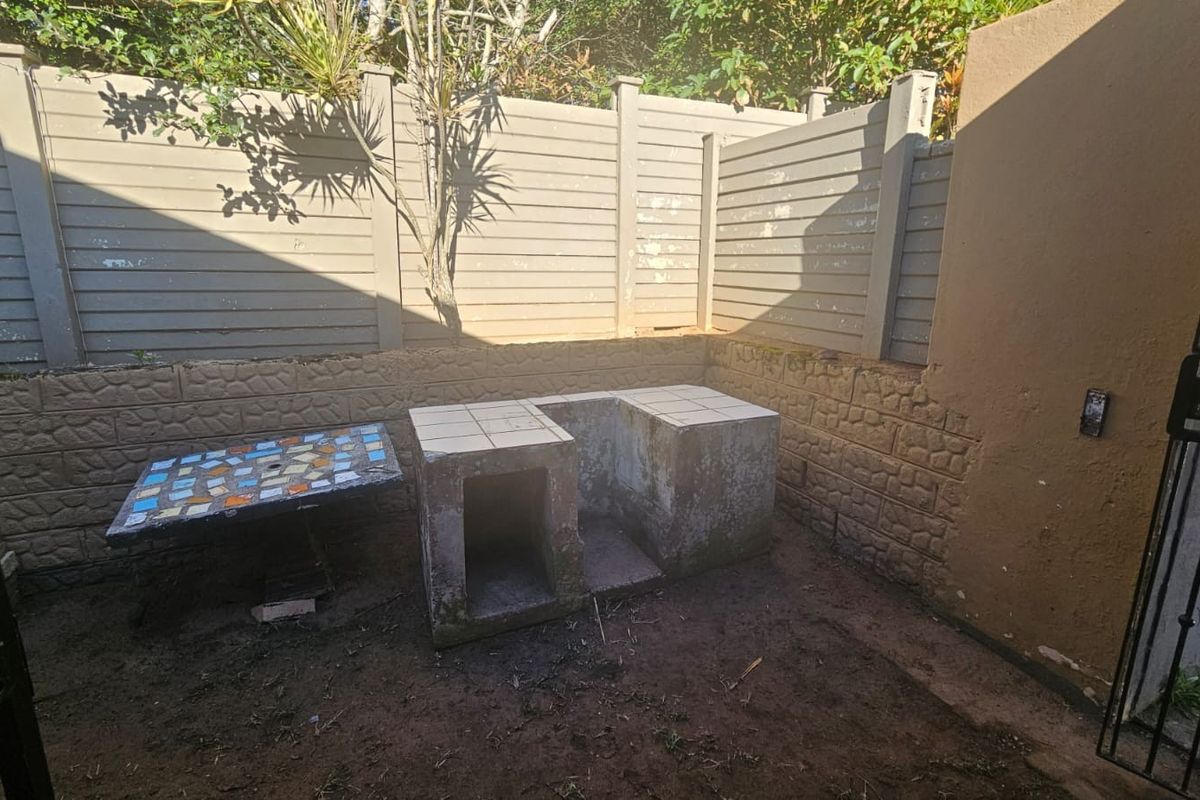Outdoor area featuring a built-in masonry braai and tiled prep surface, enclosed by a perimeter boundary wall.