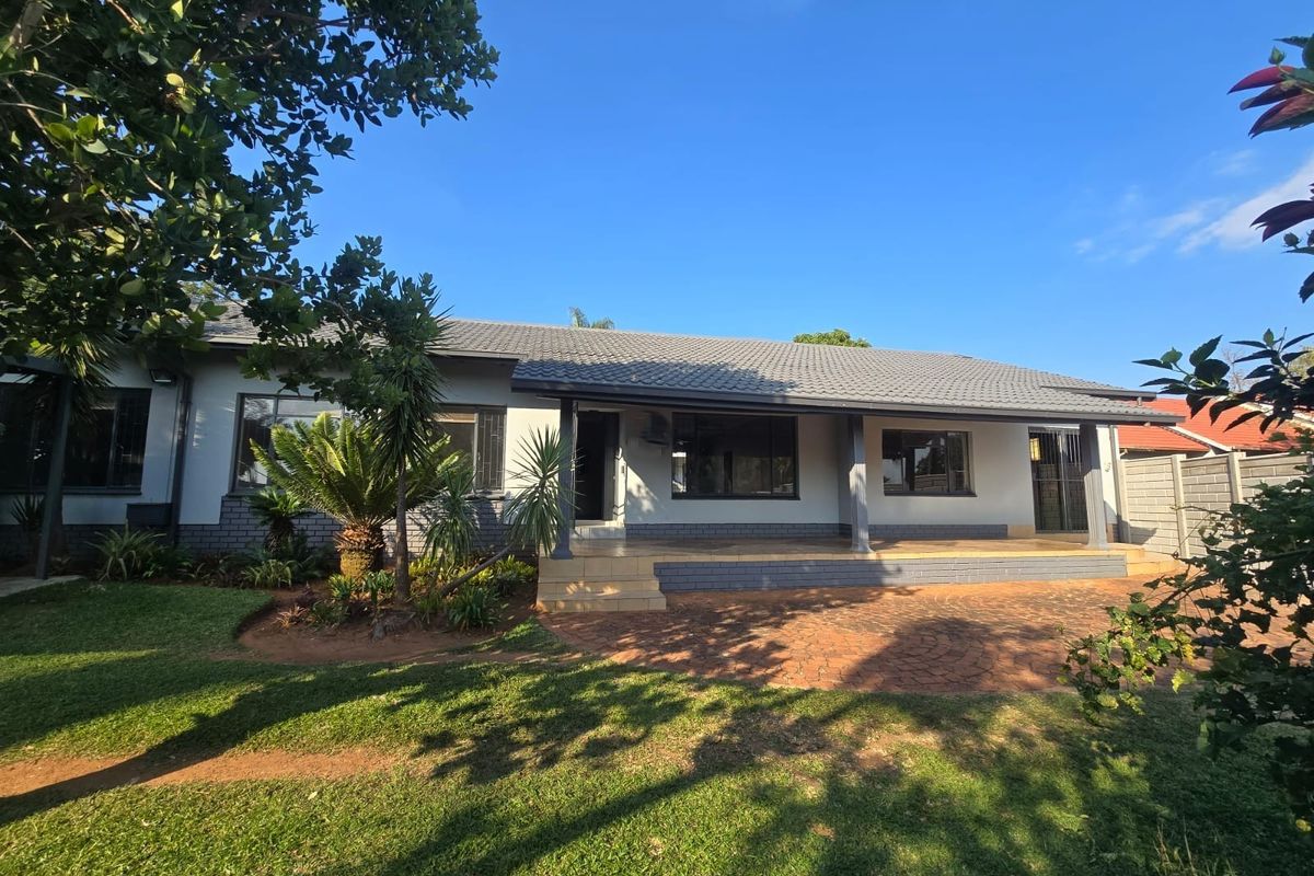 Rear view of the house featuring a covered patio, brick paving, and a well-maintained garden area.