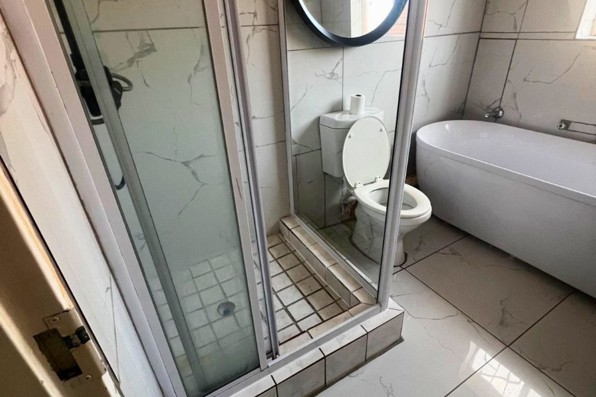 Modern bathroom featuring marble-look wall and floor tiles, a glass-enclosed shower, a freestanding bathtub, and a wall-mounted toilet.