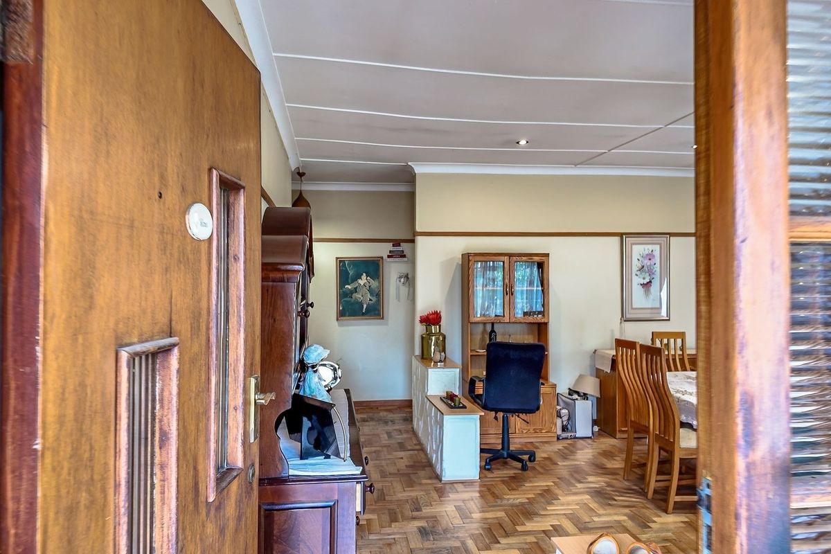 A living area featuring classic parquet flooring and coved ceilings, viewed through a timber door frame.