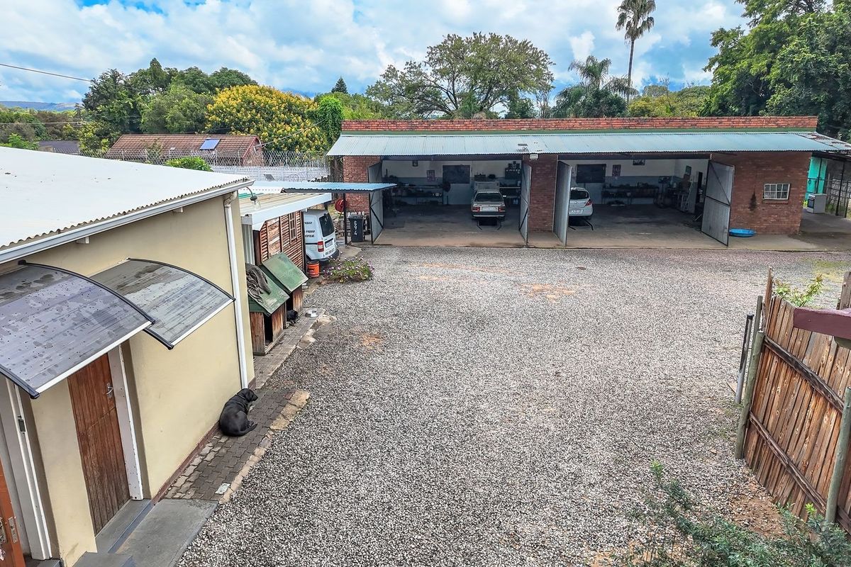 An elevated view of a commercial property featuring a multi-bay garage with brick construction and a large gravel yard area.