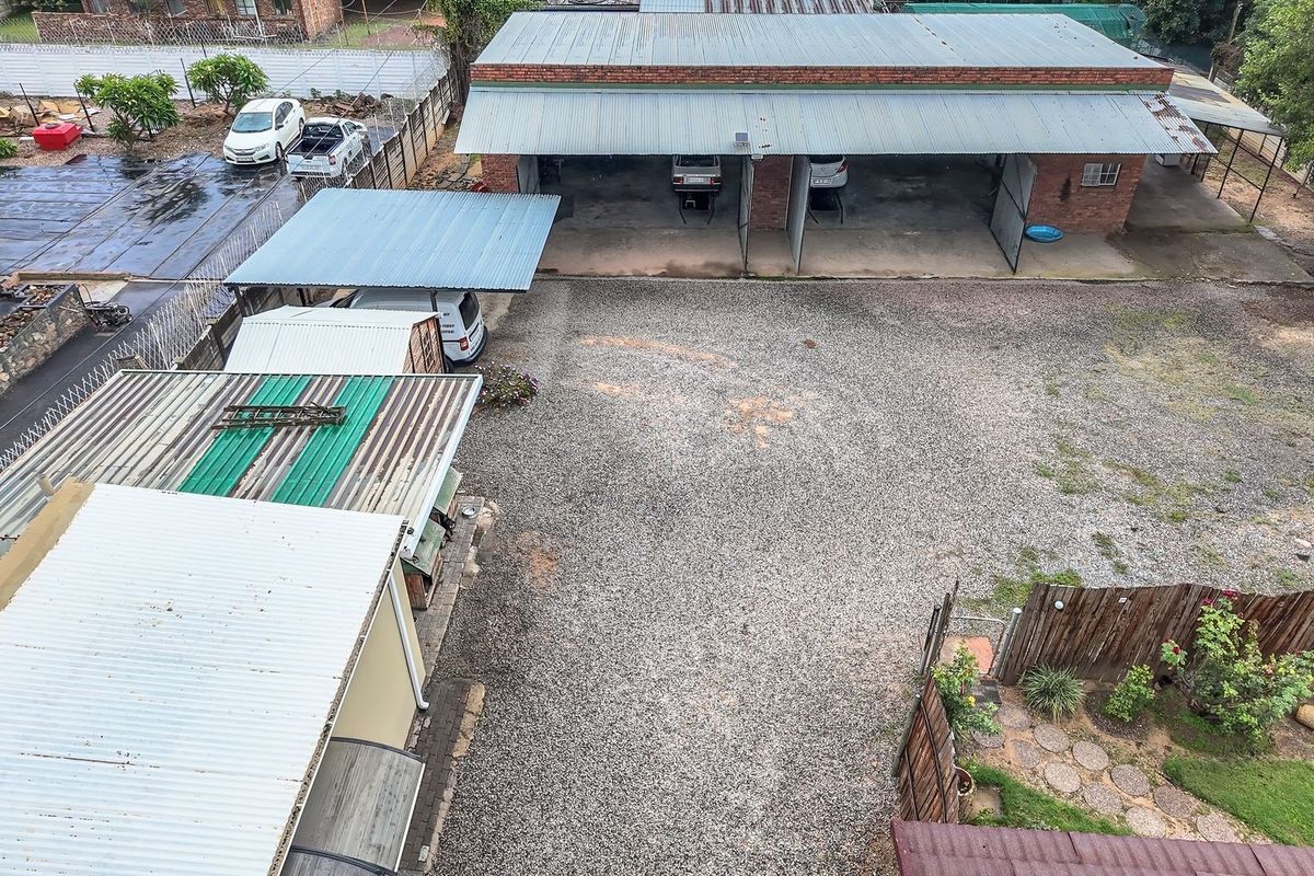 Aerial view of a commercial property featuring a gravel yard, multiple garage bays, and corrugated metal roofing structures.