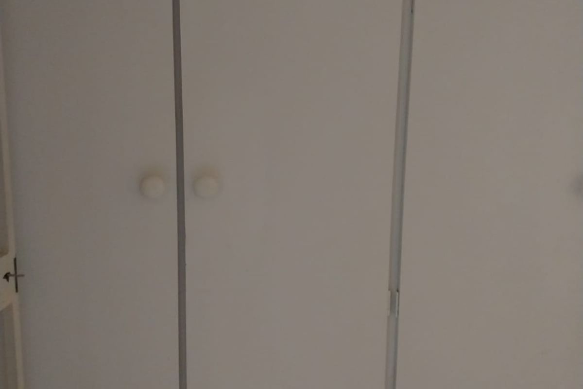 Built-in bedroom cupboards featuring white laminate doors and circular knobs, providing ample storage space.