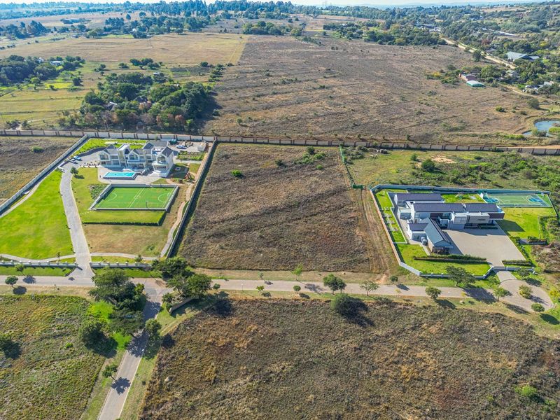 Aerial view of a vacant residential plot situated between two developed properties in a suburban estate.