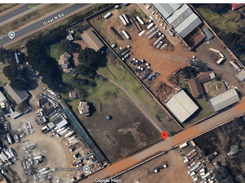 Aerial view of a commercial property site featuring multiple structures, open land, and road access.