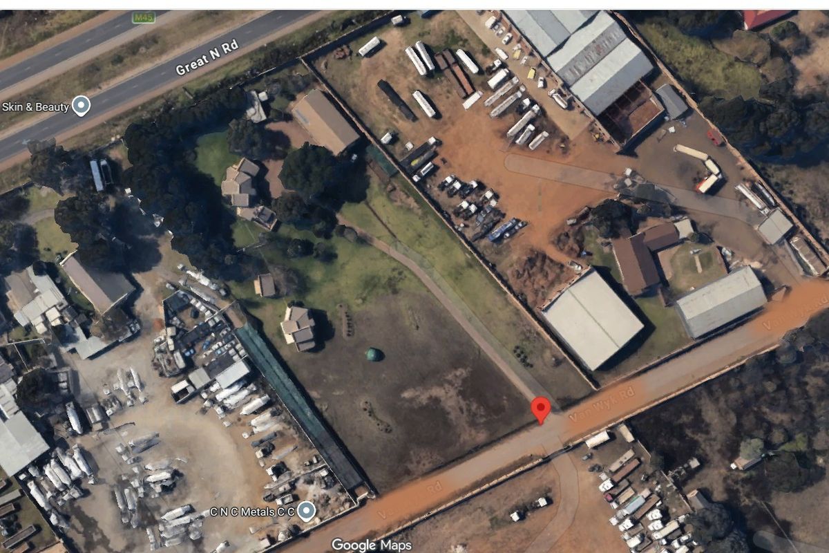 Aerial view of a commercial property site featuring multiple structures, open land, and road access.
