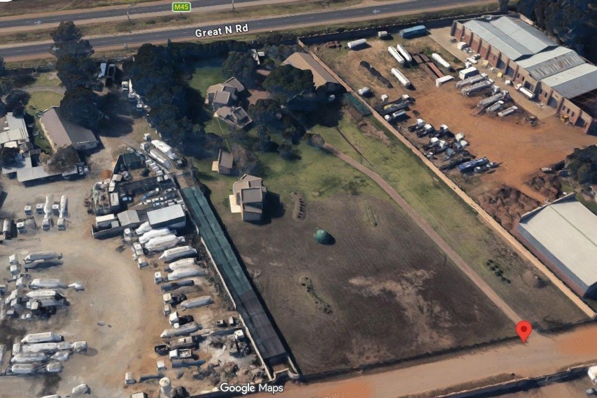 Aerial view of a commercial property site featuring open land, existing structures, and proximity to major road infrastructure.