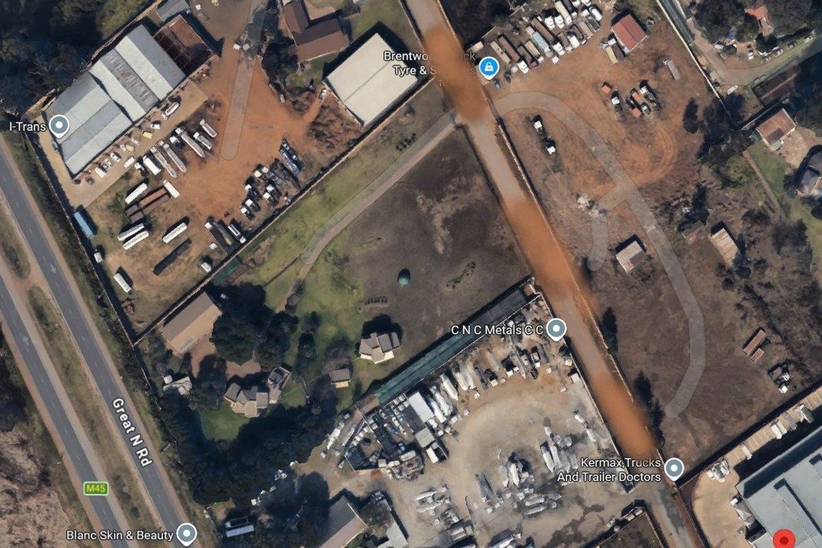 Aerial view of a commercial property site featuring multiple industrial buildings, large open yard space, and direct access to the M45 Great North Road.