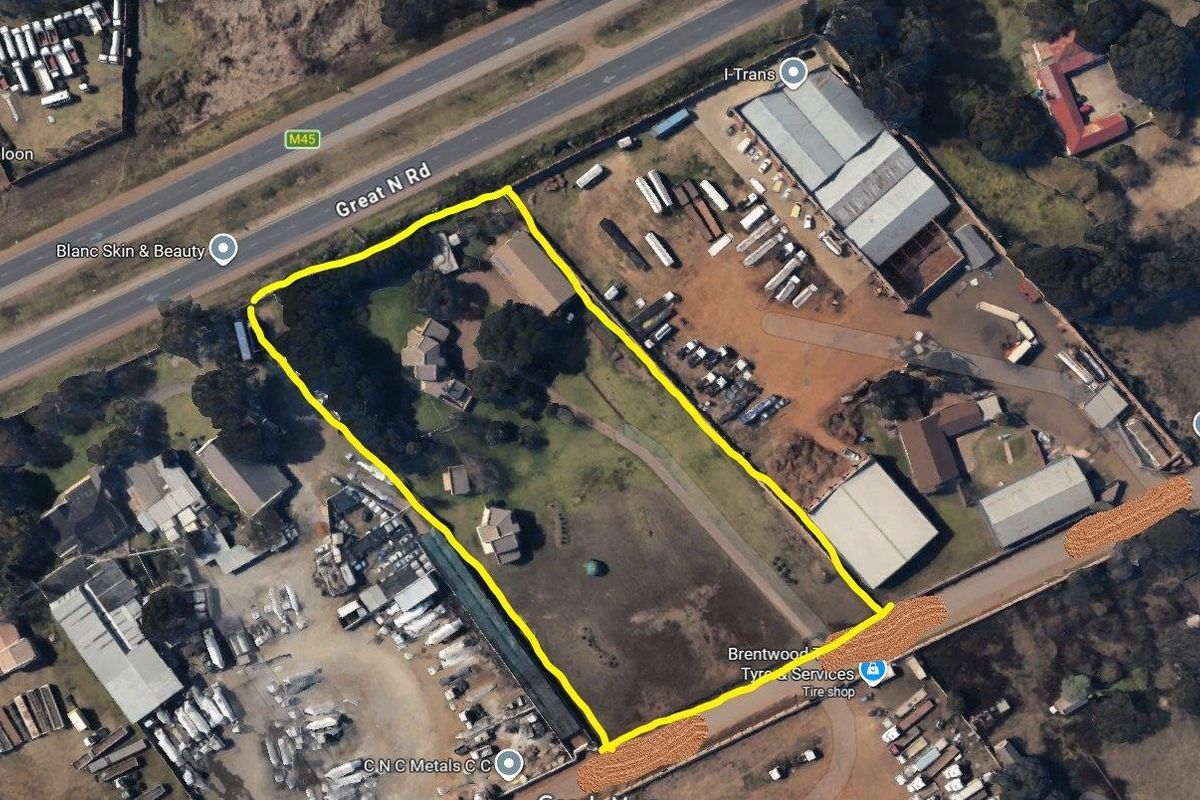 Aerial view of a commercial property plot with multiple structures, extensive grounds, and direct access to Great North Road.