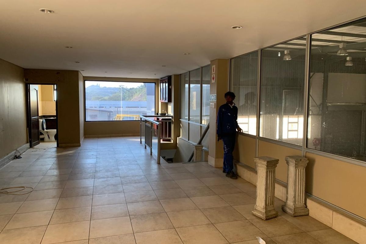 Spacious commercial hallway featuring tiled flooring, recessed lighting, and extensive glass partitioning, providing an open and bright transition area within the property.