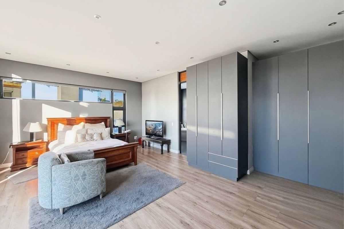 Spacious bedroom featuring modern built-in grey cabinetry, recessed ceiling lighting, and large windows providing ample natural light.