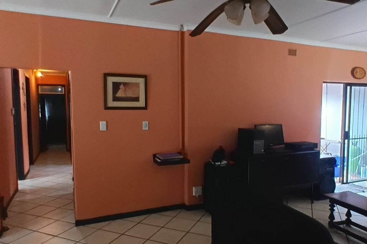 Spacious living area featuring tiled flooring, a ceiling fan, and sliding glass doors providing access to the outdoor space.