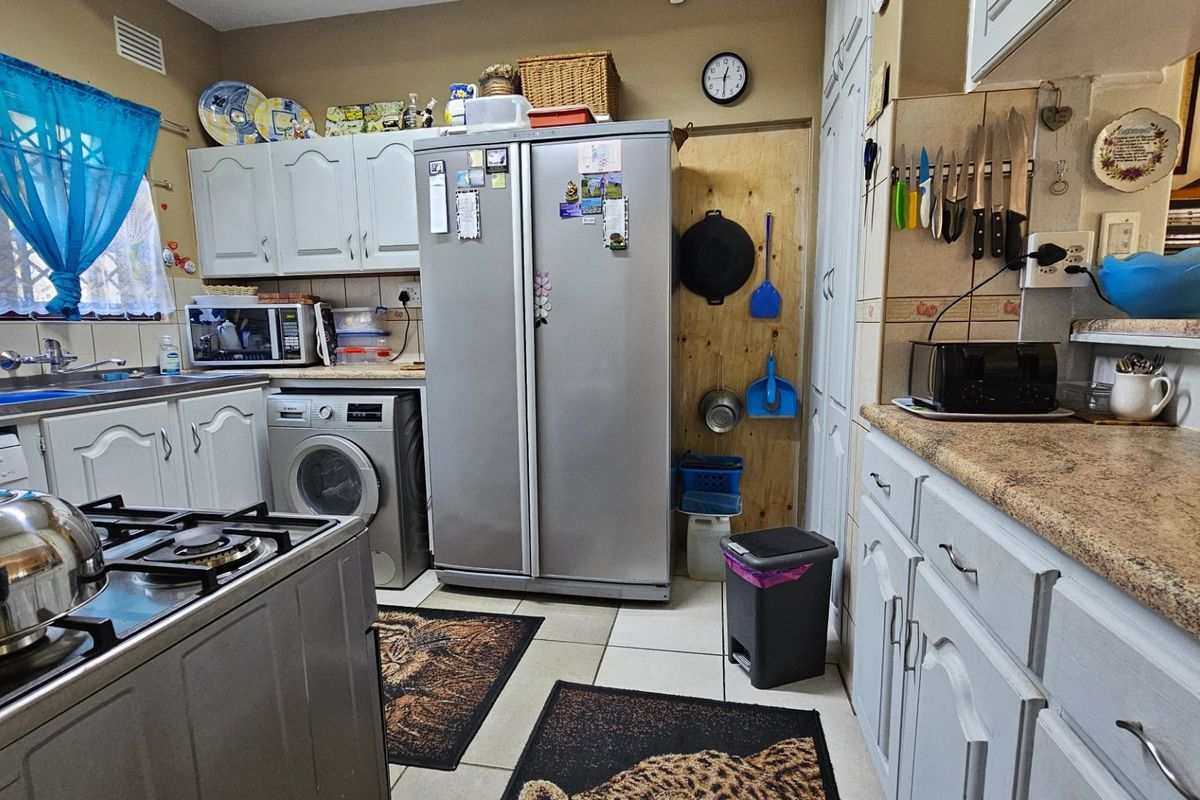 A functional kitchen featuring white cabinetry, tiled splashbacks, a gas stove, and integrated laundry space with a built-in washing machine.