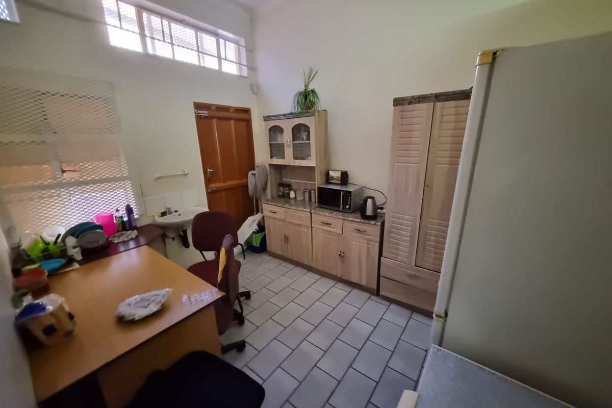 A functional kitchenette area featuring built-in cabinetry, a small sink, and tiled flooring, suitable for office or utility use.