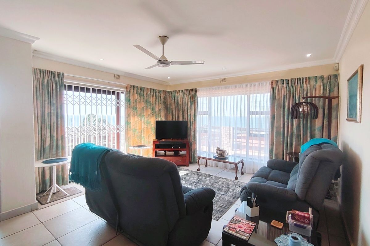 A bright living room featuring tiled flooring, recessed ceiling lighting, a central ceiling fan, and large sliding glass doors leading to an outdoor area.
