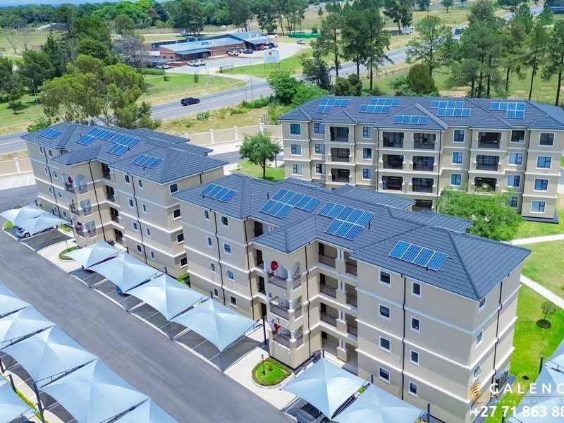 Aerial view of a modern apartment complex featuring multi-story buildings with tiled roofs, solar panels, and covered parking bays.