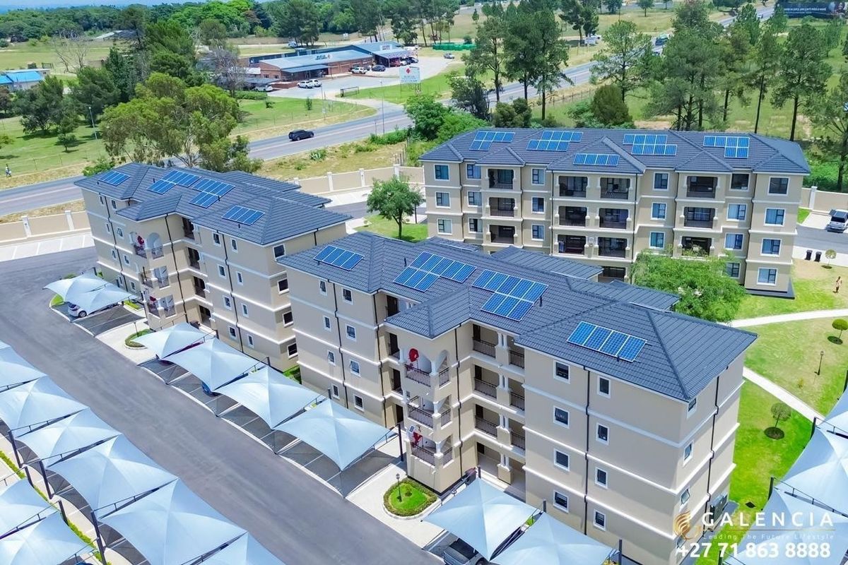 Aerial view of a modern apartment complex featuring multi-story buildings with tiled roofs, solar panels, and covered parking bays.