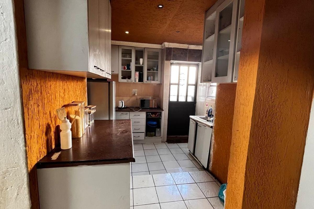 A functional kitchen featuring built-in cabinetry, tiled flooring, and direct access to an exterior door.