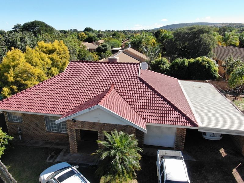 Aerial view of a townhouse featuring a red tiled roof, brick facade, attached garage, and a covered carport area.