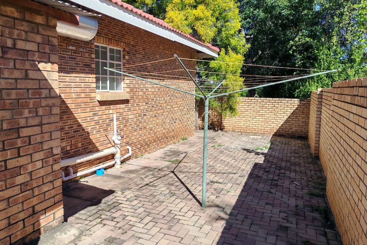A private rear courtyard featuring paved flooring, face-brick walls, and a rotary clothesline, providing a functional outdoor utility space.