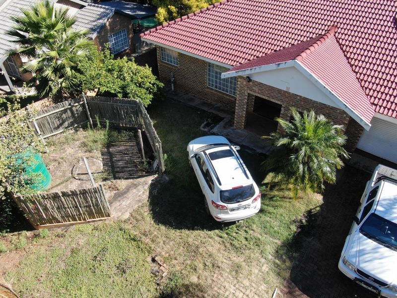 Aerial view of the townhouse exterior featuring a tiled roof, brick facade, and a private garden area with established landscaping.