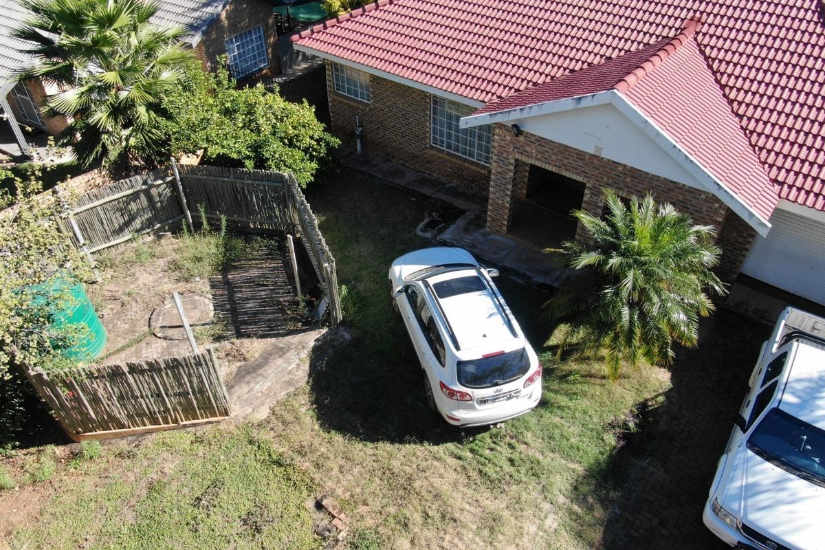 Aerial view of the townhouse exterior featuring a tiled roof, brick facade, and a private garden area with established landscaping.
