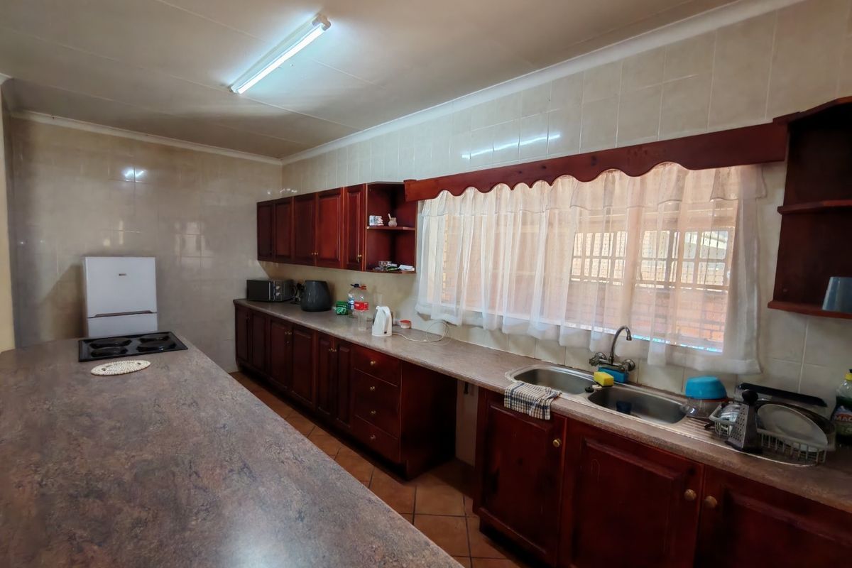 A functional kitchen featuring dark wood cabinetry, tiled walls, a double basin sink, and a large breakfast bar counter.
