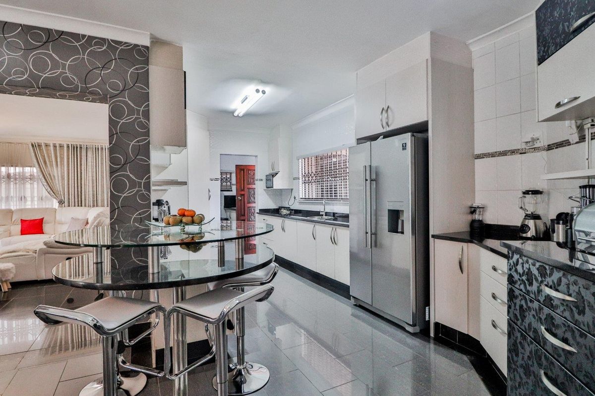 Modern kitchen featuring sleek cabinetry, granite countertops, tiled flooring, and an integrated breakfast bar area, seamlessly flowing into the adjacent living space.