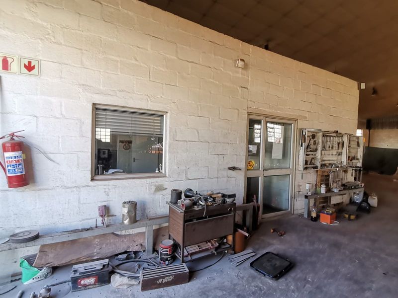 Industrial workshop area featuring exposed blockwork walls, a metal-framed glass partition, and integrated wall-mounted tool storage.