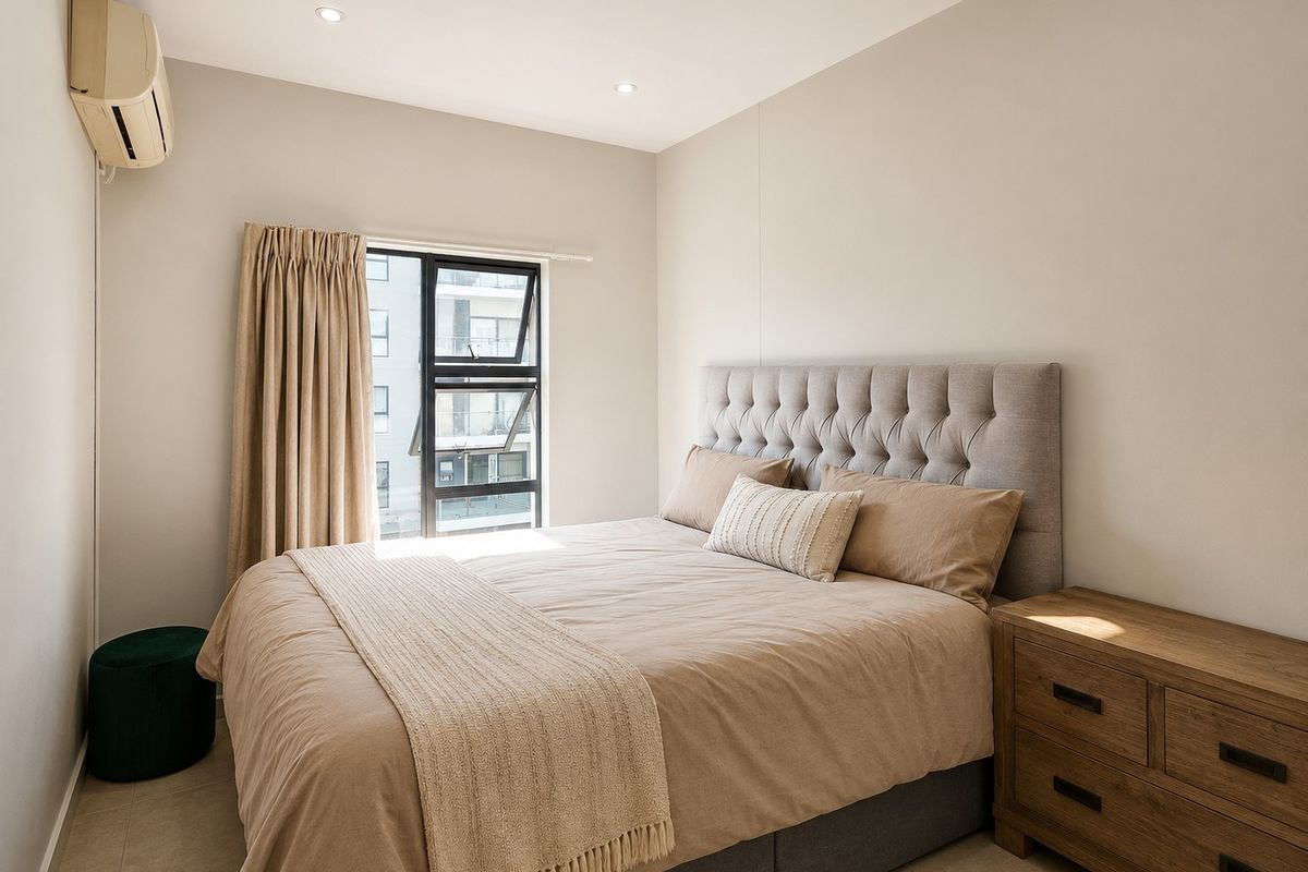 A well-maintained bedroom featuring neutral tones, tiled flooring, recessed lighting, and a wall-mounted air conditioning unit.