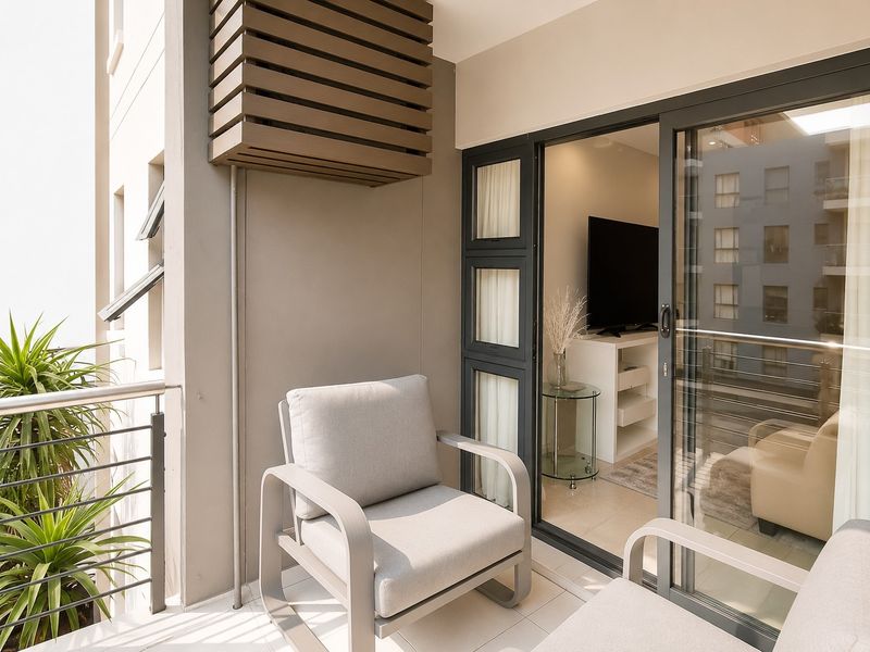 A modern apartment balcony featuring tiled flooring, a metal railing, and a built-in air conditioning unit enclosure, accessible via sliding glass doors.