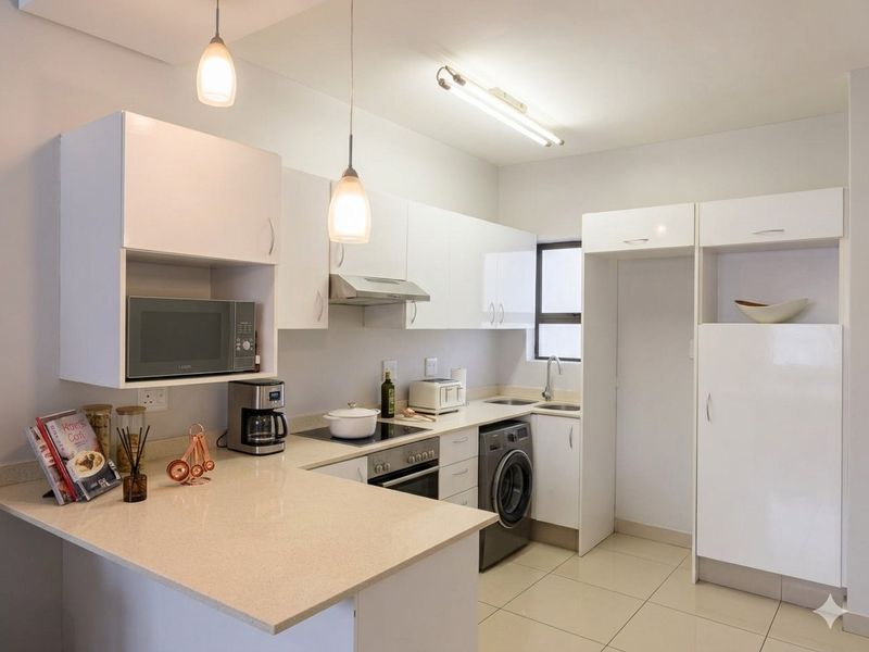 Modern kitchen featuring white cabinetry, stone countertops, integrated oven, hob, extractor fan, and dedicated space for a washing machine.