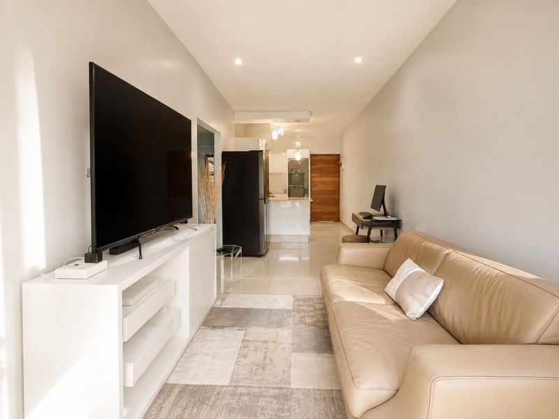 An open-plan living area featuring tiled flooring, recessed lighting, and a seamless transition into the kitchen space.