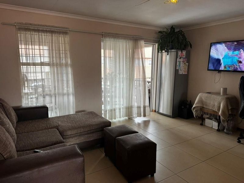 A living room featuring large sliding glass doors that provide access to an outdoor balcony area, finished with neutral floor tiles.