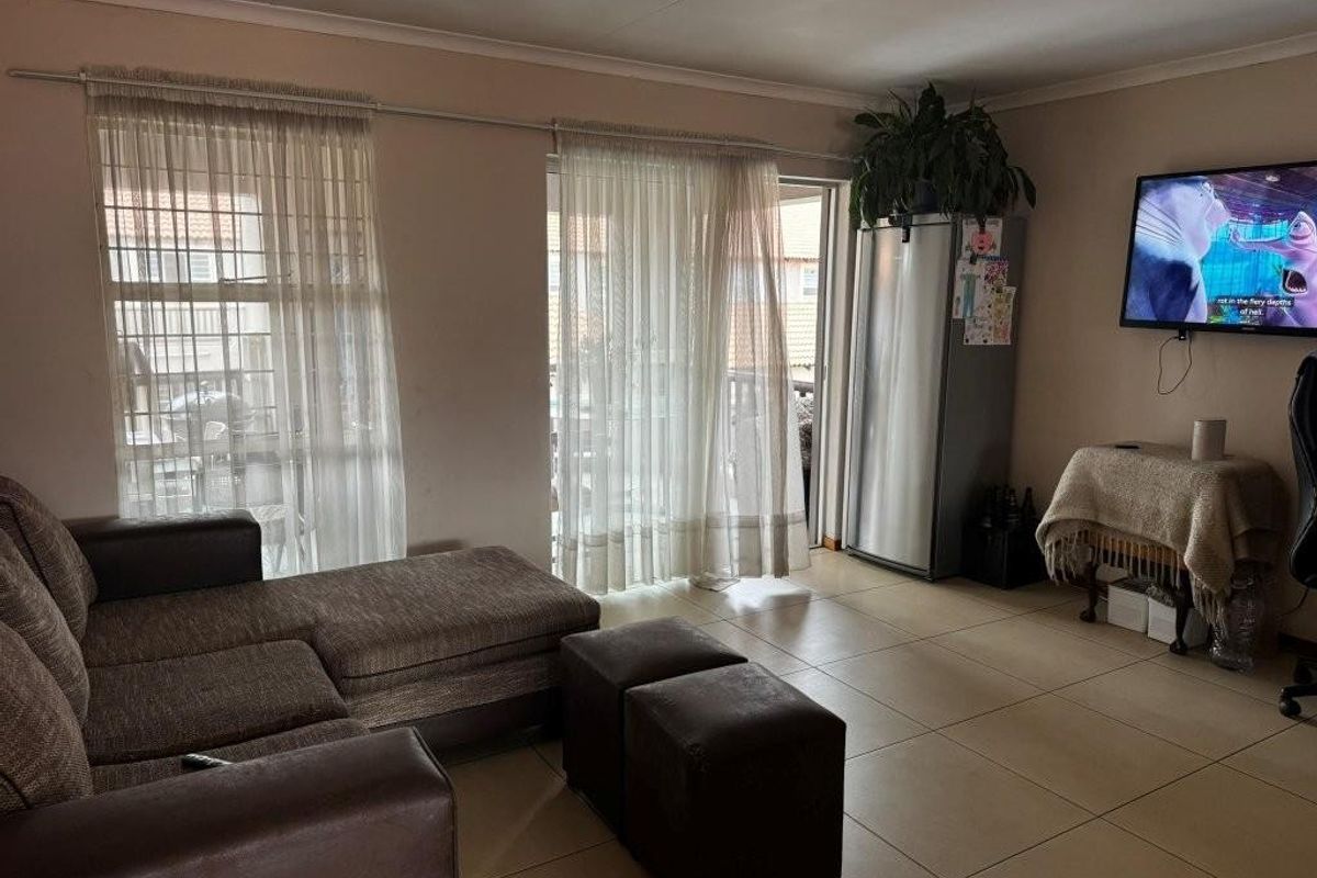 A living room featuring large sliding glass doors that provide access to an outdoor balcony area, finished with neutral floor tiles.