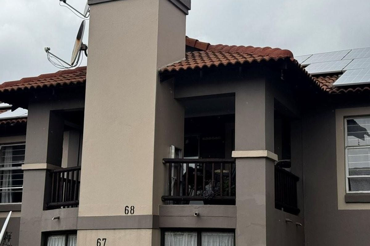 Exterior view of an apartment building featuring a balcony, tiled roof, and solar panels.